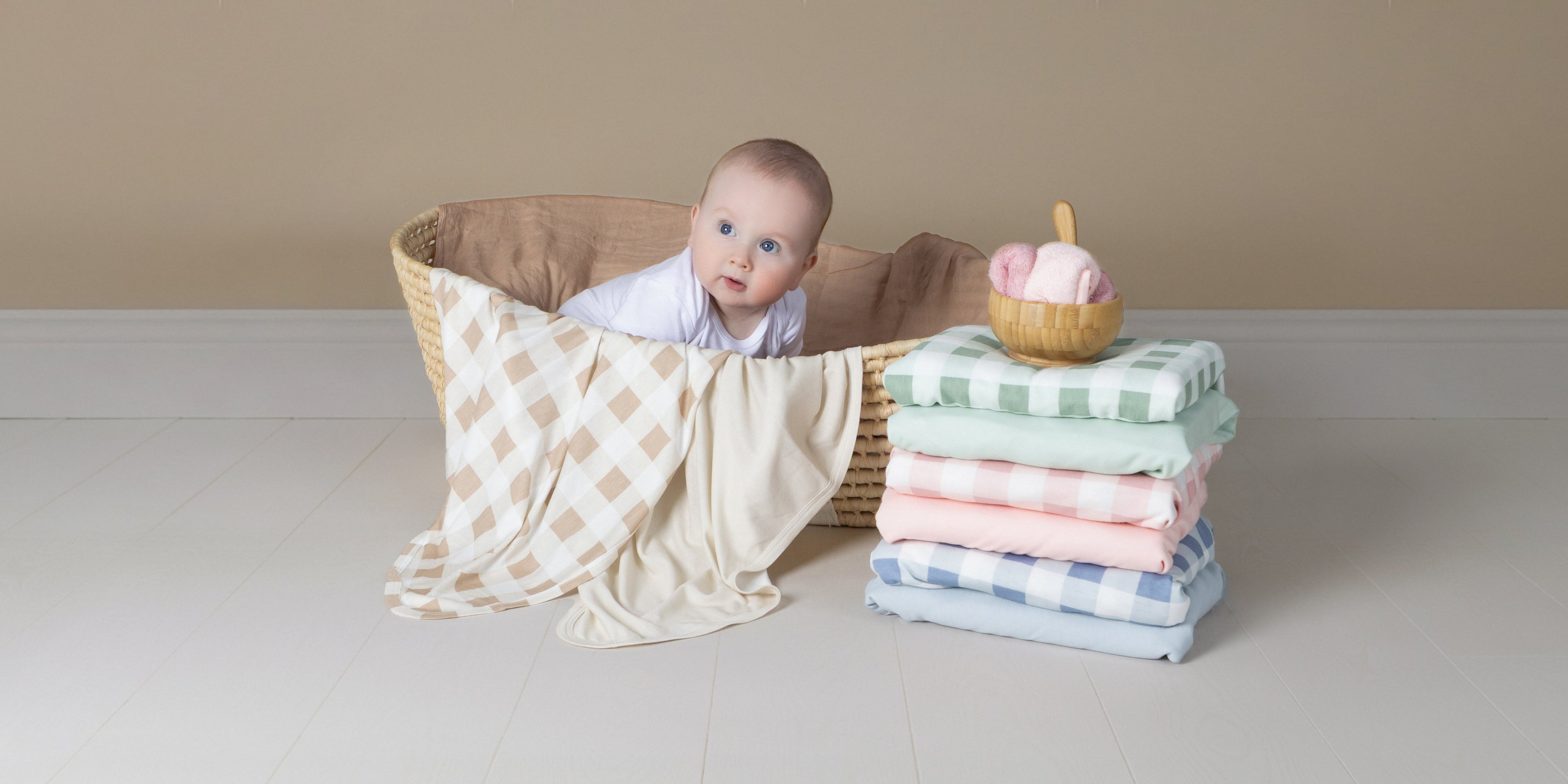 cute baby sitting in a basket of fleece blankets with nordic prints